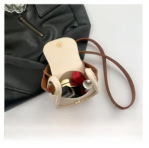 Internal view of cream mini saddle bag showing storage space for lipstick and makeup