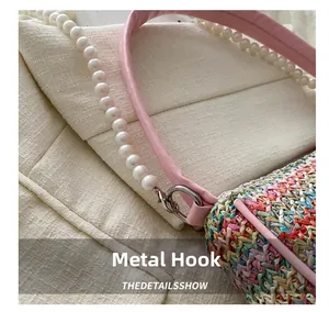 Gros plan du crochet en métal brillant et de la bandoulière perle du sac en paille