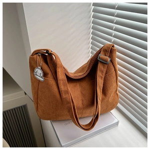 Detail of brown corduroy tote bag with vertical texture and cute dog pendant