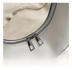 Detailed close-up of a white leather bag featuring silver zippers and a pink heart charm