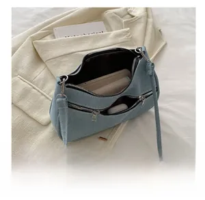 Dual-zipper denim underarm bag showing interior capacity for phone and accessories