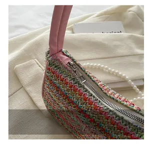 Détail d'un sac à main tissé coloré avec fermeture éclair argentée et chaîne de perles