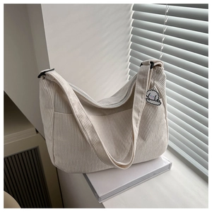 Detail of off-white corduroy tote bag featuring a cute white dog charm and adjustable strap