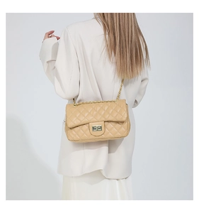 Detailed view of beige quilted faux leather bag with gold metal twist lock and chain strap