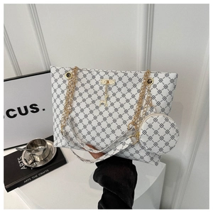 Close-up of white tote bag with black pattern, gold chain, and deer charm accessory