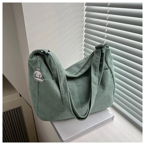 Detail of corduroy shoulder bag texture in sage green with a cute plush puppy charm