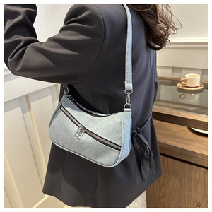 Dettaglio della borsa a spalla in denim azzurro indossata con un blazer grigio