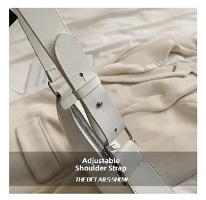 Detail shot of white leather crescent bag featuring adjustable shoulder strap and silver buckle