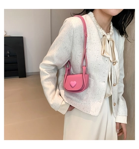 Close-up of pink leather mini saddle bag with heart decoration and shoulder strap