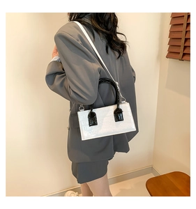 Rear view of model wearing white faux crocodile leather handbag with black handles