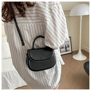 Detailed view of a black saddle bag worn cross-body to show size and strap length