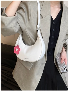 Detailed shot of a white hobo bag with a pink flower charm and zipper closure
