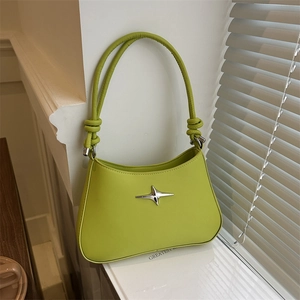 Lime green leather underarm bag with silver star detail and knot strap on window sill