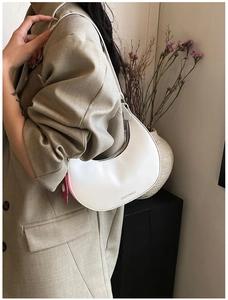 Minimalist white crescent hobo bag with elephant charm on model's shoulder