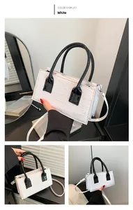 Detailed view of white crocodile pattern leather handbag with contrasting black handles