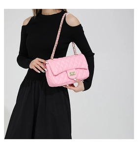 Close-up of pink quilted leather crossbody bag with gold chain strap on model