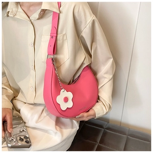 Close-up of pink crescent saddle bag with heart-flower charm and adjustable strap