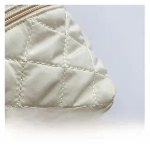 Vista macro del tessuto trapuntato beige con cuciture a rombi e dettaglio zip