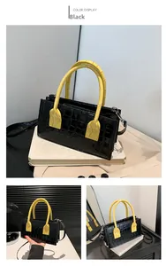 Detail of a chic black crocodile pattern handbag with contrast yellow handle and strap