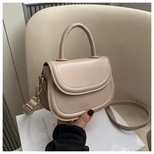 Detail of beige saddle bag showing adjustable leather strap and gold metal hardware