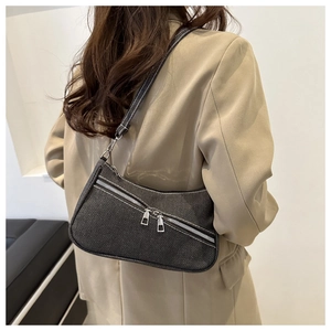 Dettaglio della borsa baguette in denim con cerniere argentate su blazer beige