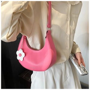 Close-up of pink crescent hobo bag with matte leather texture and white floral charm