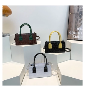 Macro detail of three mini crocodile pattern handbags with contrast color handles on display