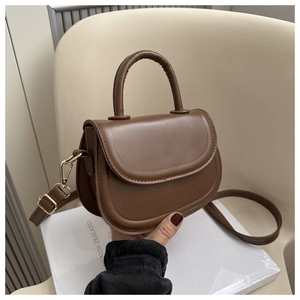 Detail view of a dark brown saddle bag featuring decorative stitching and golden hardware