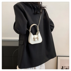 Detailed back view of a mini white bow handbag with gold chain strap and smooth leather texture