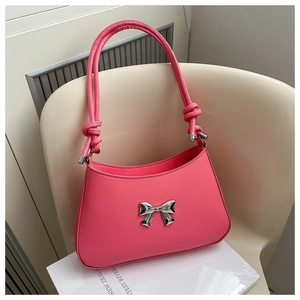 Detail of pink handbag featuring a silver bow accent and unique knotted leather handle