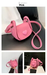 Detail of mini pink saddle bag with 3D heart decoration and adjustable crossbody strap