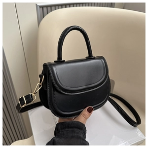 Close-up of black retro saddle bag with gold metal buckle and sleek leather texture