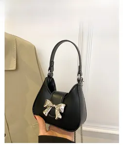 Close-up of a black crescent handbag featuring a metallic bow and elegant silver chain