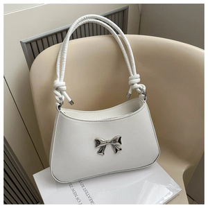 Detailed shot of twisted handle and silver metal bow on a white PU leather shoulder bag