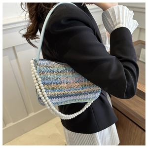 Détail du sac baguette tissé coloré avec broderie papillon et bandoulière en perles