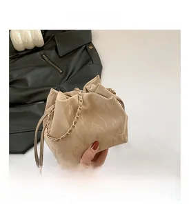 Detail view of beige pleated bucket bag featuring soft glossy leather and gold chain strap