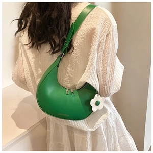 Detail view of a green crescent saddle bag featuring a smooth PU finish and white flower charm