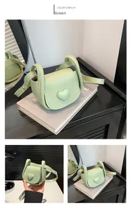 Detail of mint green mini saddle bag with heart ornament and adjustable strap