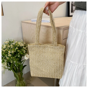 Dettaglio ravvicinato della borsa tote in paglia beige con trama a spina di pesce