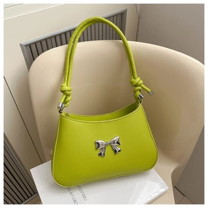 Detail of neon green crossbody bag with silver bow accent and knotted handle strap