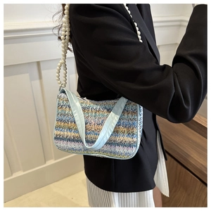 Detail of colorful woven shoulder bag featuring butterfly embroidery and pearl strap