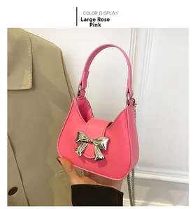 Detail of rose red semi-circle handbag featuring a silver metallic bow and chain strap