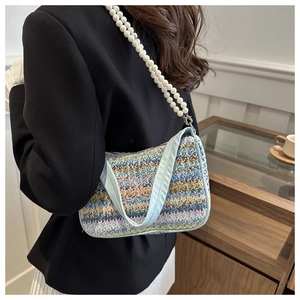 Detail of colorful woven handbag with butterfly embroidery and pearl shoulder strap