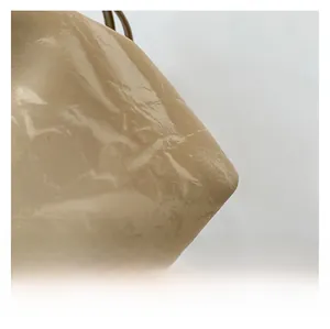Close-up of beige shiny bucket bag showing pleated leather texture and glossy finish