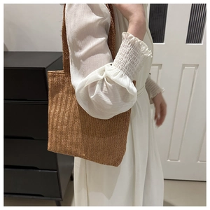 Dettaglio della borsa tote in paglia intrecciata con trama fine e tracolla marrone
