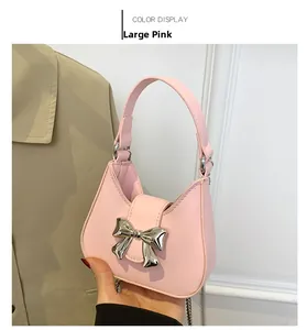 Detailed view of pink shoulder bag featuring a silver metal bow accent and smooth PU texture
