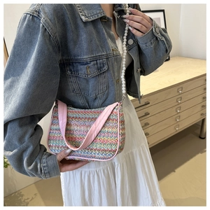 Close-up of rainbow woven bag featuring pink butterfly embroidery and pearl shoulder strap