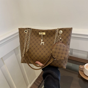 Brown tote bag with geometric pattern, gold chain strap, and stag pendant in cafe setting