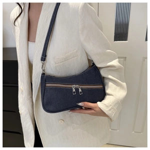 Dettaglio borsa sottobraccio in denim blu con doppia cerniera e blazer bianco
