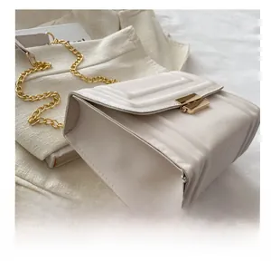 Seitenansicht der cremefarbenen Stepptasche mit goldener Kette und Metallschnalle